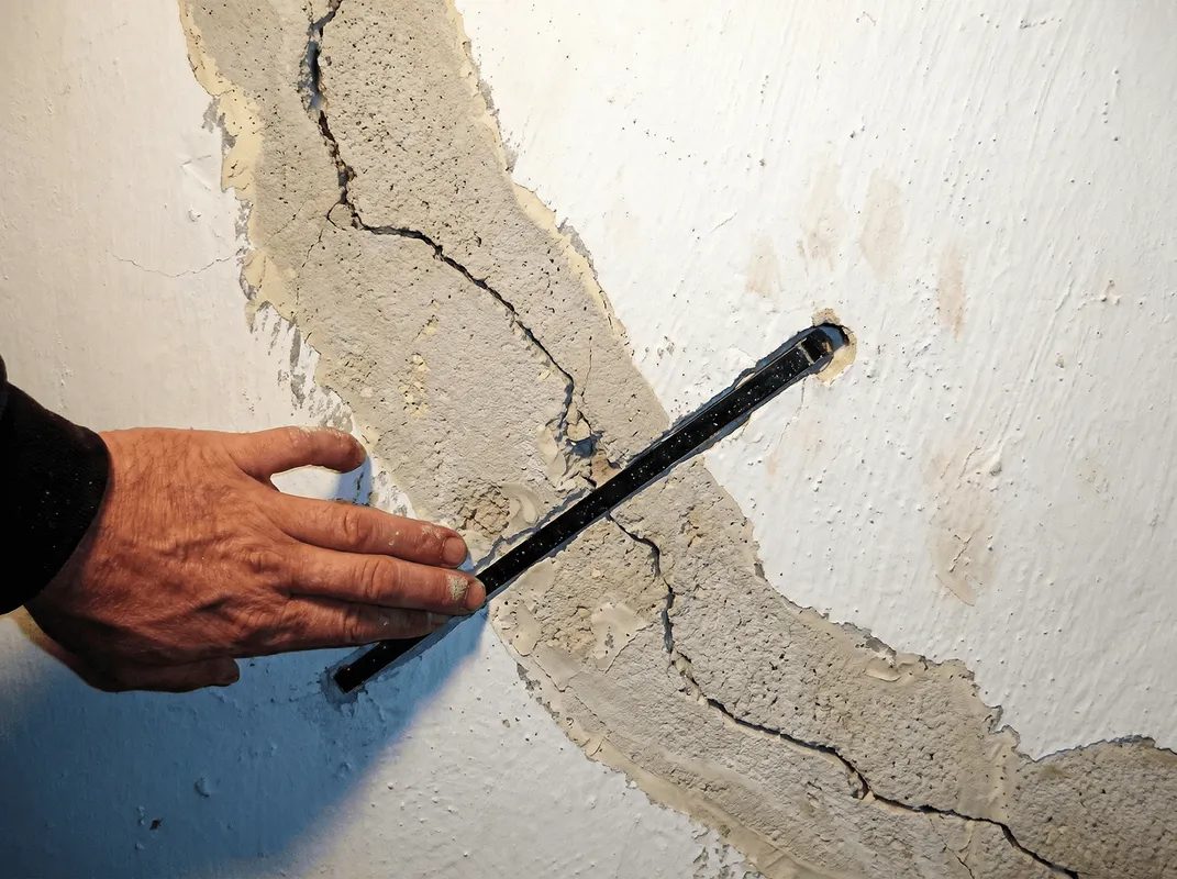 A wall with a large crack is being inspected by a professional in San Jose, CA